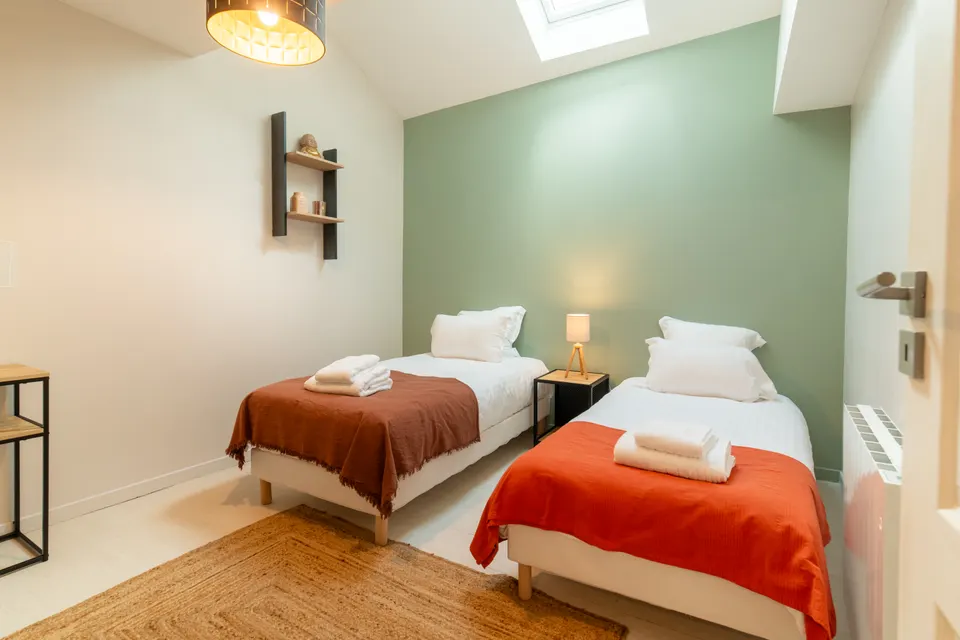 Chambre du Domaine La Roche avec deux lits et un mur vert sauge